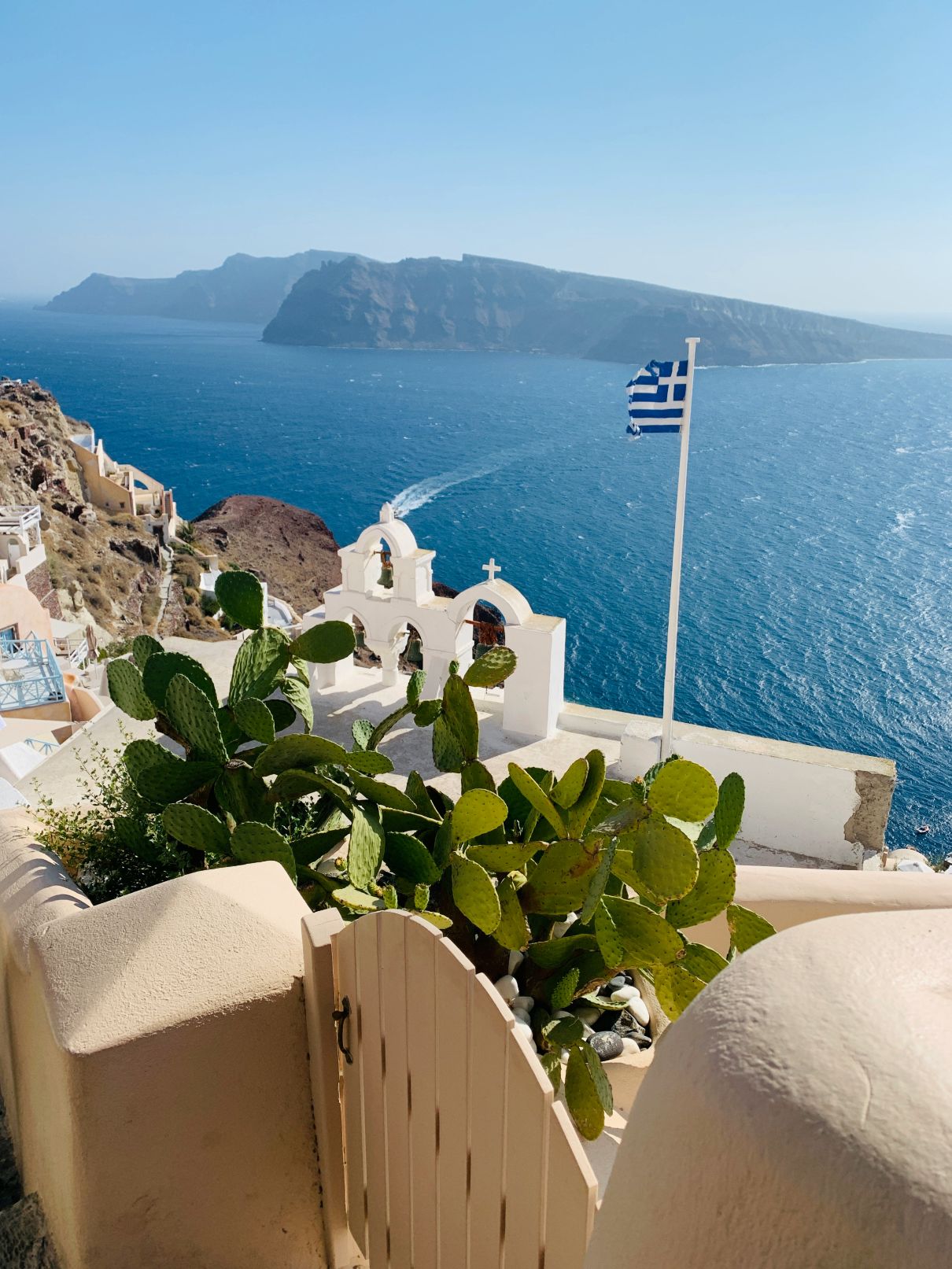 Greek flag on a church in Santorini with blue sea in the background