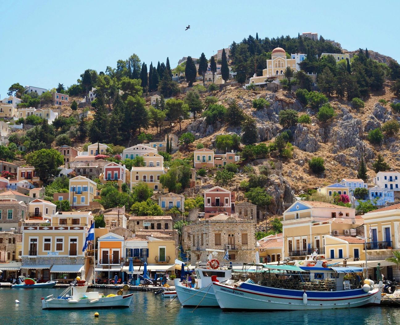 Boats and houses along a cliff on a Greek island